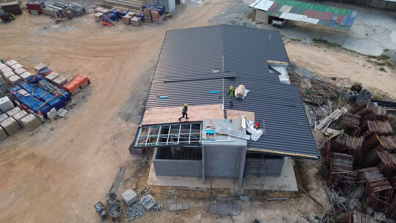 Completed dark metal roof covering beside a roadway